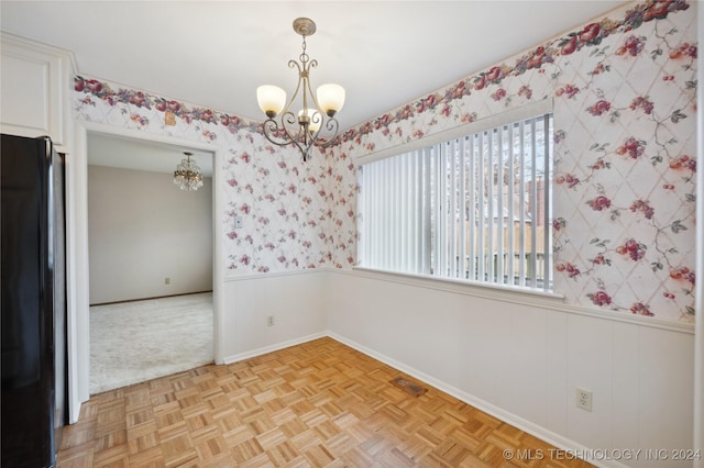 empty room with light parquet floors and a notable chandelier