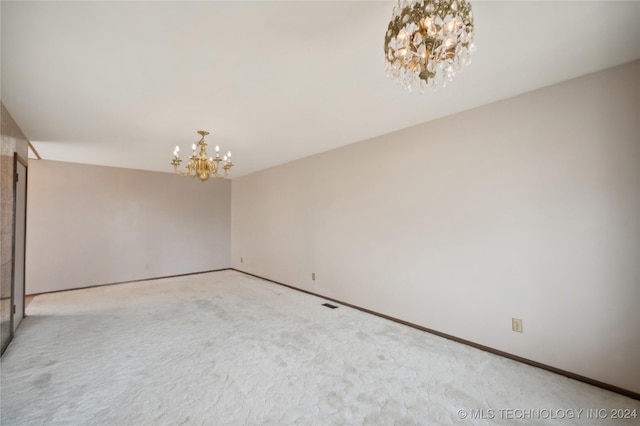 carpeted spare room with an inviting chandelier