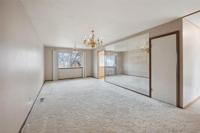 carpeted empty room with a notable chandelier