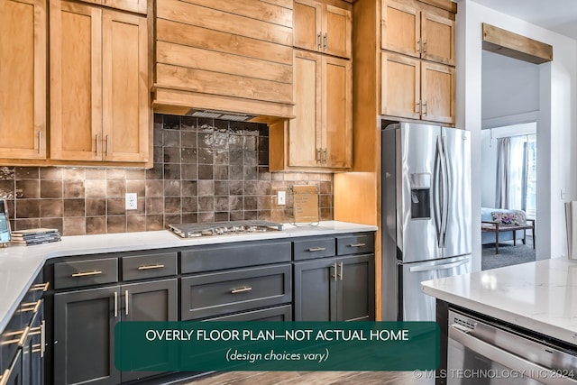 kitchen with light stone countertops, premium range hood, gray cabinets, decorative backsplash, and appliances with stainless steel finishes