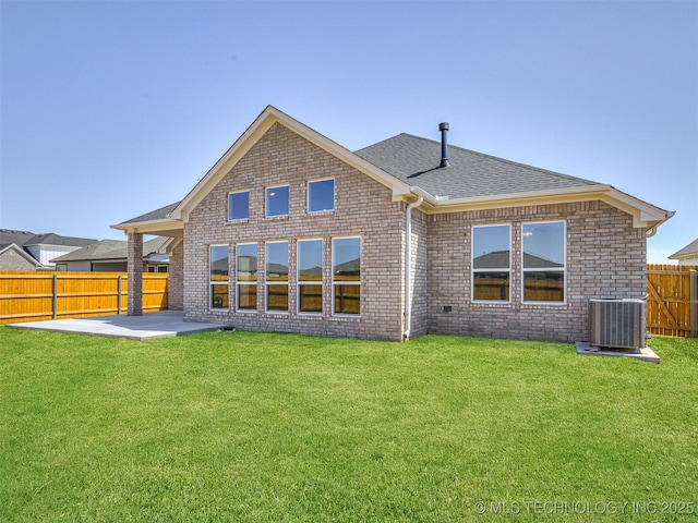 back of house featuring roof with shingles, a fenced backyard, central AC unit, brick siding, and a patio