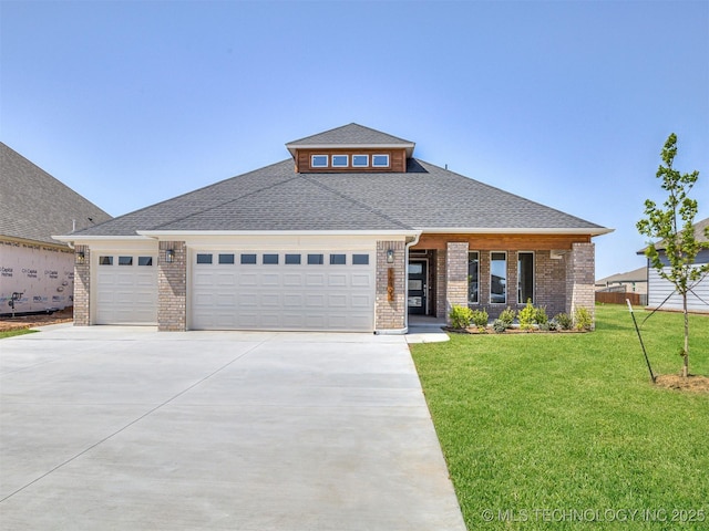 prairie-style home with a garage, driveway, a shingled roof, a front yard, and brick siding
