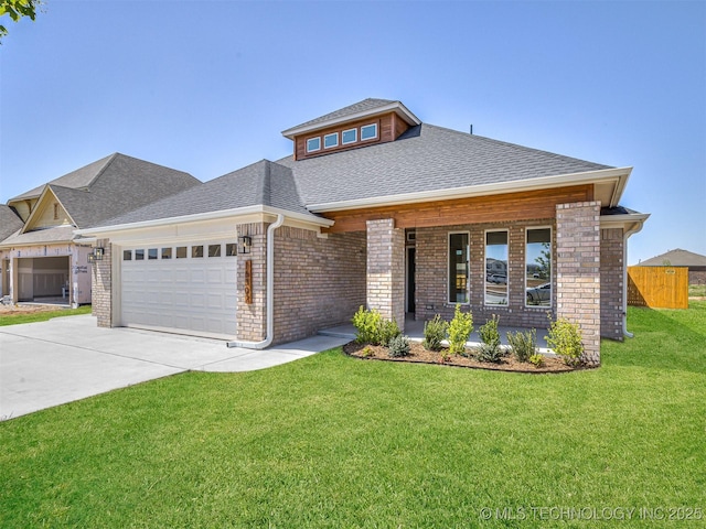 prairie-style home featuring a shingled roof, a front lawn, concrete driveway, brick siding, and a garage
