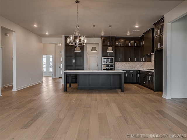 kitchen featuring decorative backsplash, appliances with stainless steel finishes, light wood-style floors, and light countertops