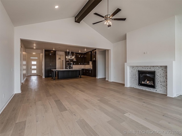 unfurnished living room with light wood-style flooring, a glass covered fireplace, beamed ceiling, ceiling fan, and high vaulted ceiling