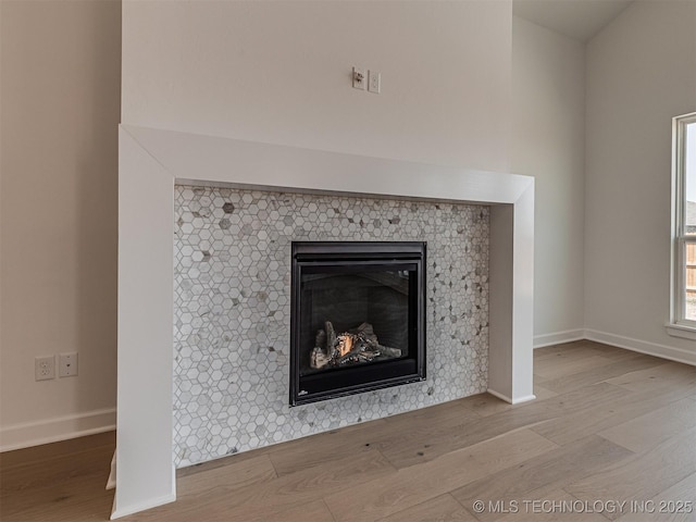 room details with baseboards, wood finished floors, and a tiled fireplace