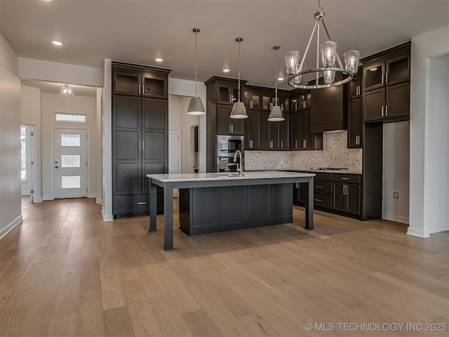 kitchen featuring stainless steel appliances, an inviting chandelier, light countertops, backsplash, and dark brown cabinets