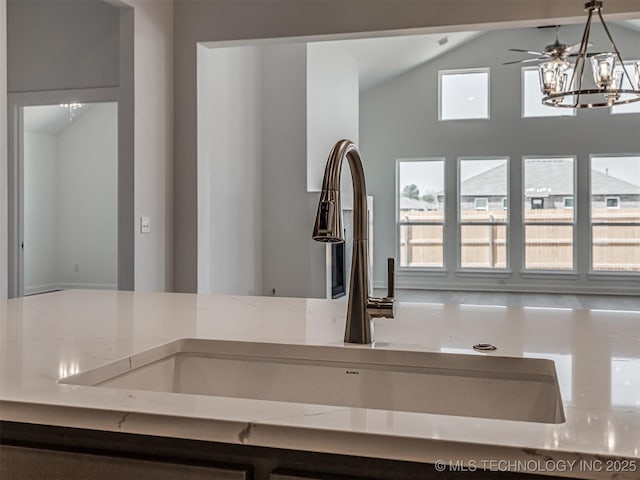details featuring a notable chandelier, light stone counters, a sink, and decorative light fixtures