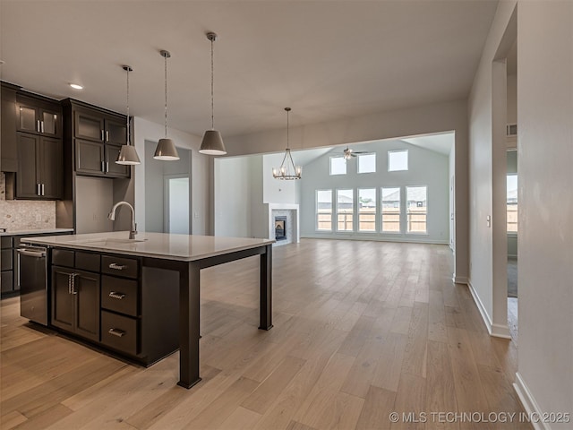 kitchen with light countertops, a sink, light wood-type flooring, a fireplace, and ceiling fan