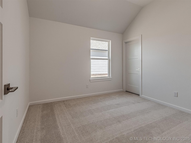 spare room featuring vaulted ceiling, baseboards, and light colored carpet