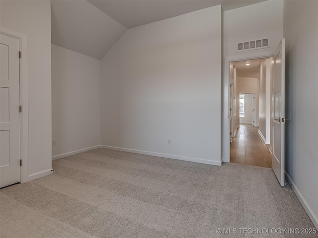 unfurnished bedroom with baseboards, carpet flooring, vaulted ceiling, and visible vents