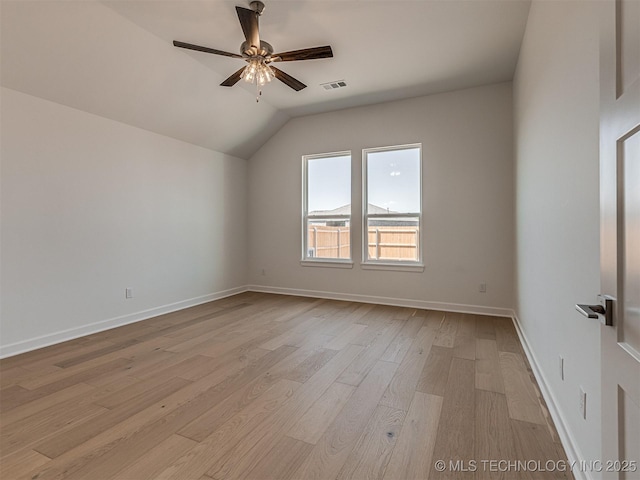 interior space featuring light wood finished floors, vaulted ceiling, visible vents, a ceiling fan, and baseboards