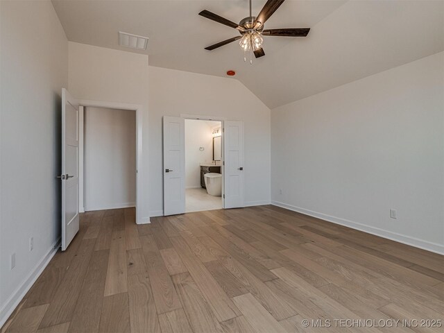 unfurnished bedroom featuring light wood finished floors, baseboards, ensuite bath, lofted ceiling, and visible vents