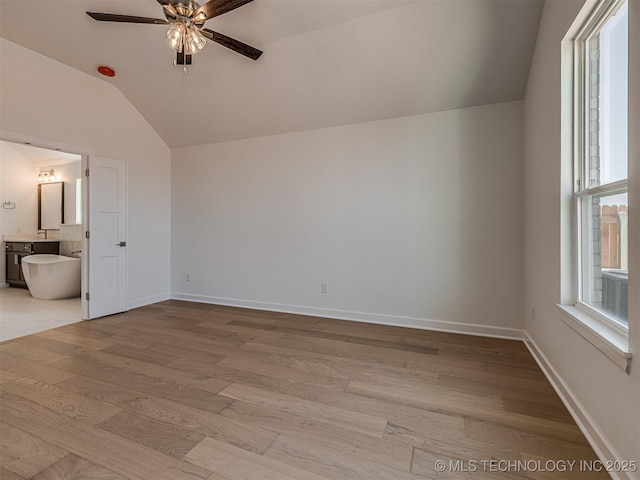 unfurnished bedroom featuring vaulted ceiling, connected bathroom, light wood-style floors, ceiling fan, and baseboards