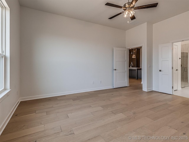 unfurnished bedroom featuring ceiling fan, baseboards, a sink, and light wood-type flooring