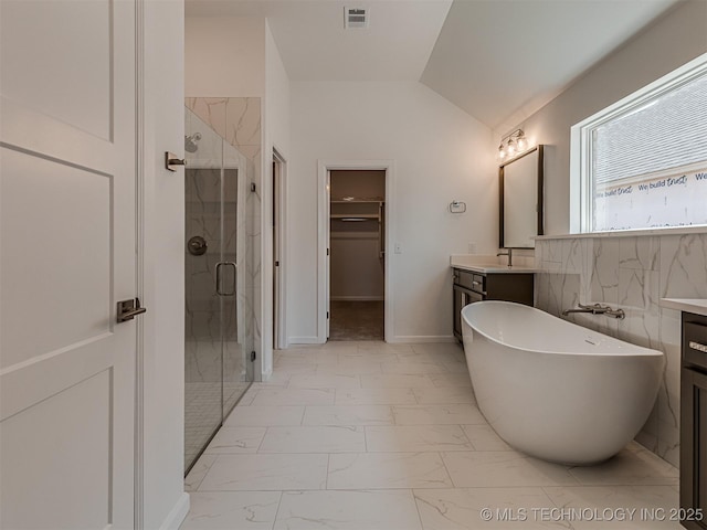 bathroom featuring a stall shower, a walk in closet, marble finish floor, a freestanding bath, and visible vents