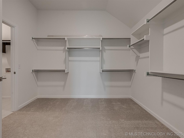 spacious closet featuring vaulted ceiling and carpet flooring
