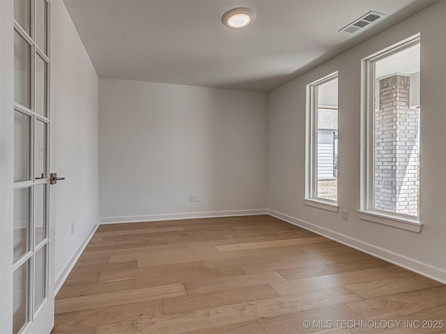 unfurnished room featuring visible vents, light wood finished floors, and baseboards
