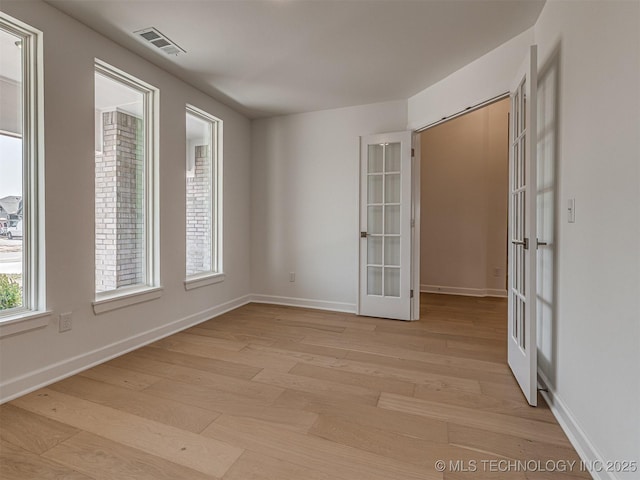 spare room with baseboards, french doors, light wood-style floors, and visible vents