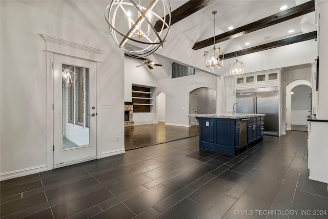 kitchen featuring blue cabinets, beam ceiling, a center island with sink, white cabinets, and hanging light fixtures