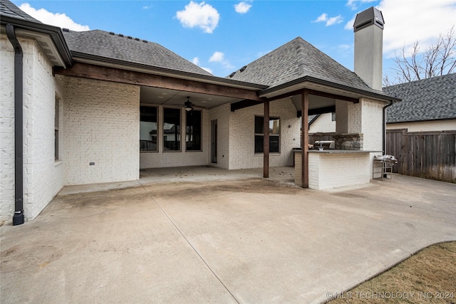 back of property with ceiling fan, a patio area, and an outdoor kitchen