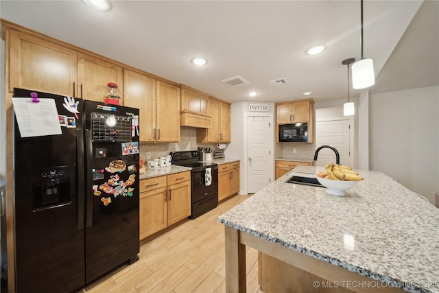 kitchen featuring decorative backsplash, light stone counters, sink, black appliances, and hanging light fixtures