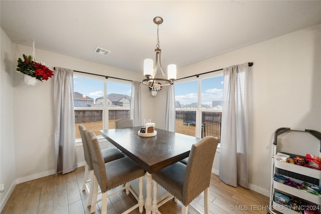 dining room with plenty of natural light, light wood-type flooring, and an inviting chandelier