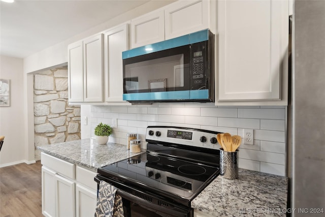 kitchen with white cabinets, light stone countertops, stainless steel electric range oven, tasteful backsplash, and light hardwood / wood-style floors