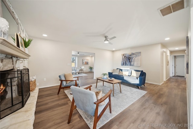 living room featuring ceiling fan, a fireplace, and hardwood / wood-style flooring