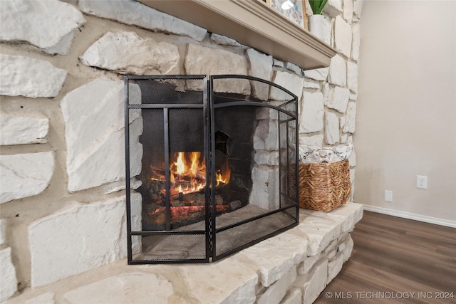 room details featuring a stone fireplace and wood-type flooring