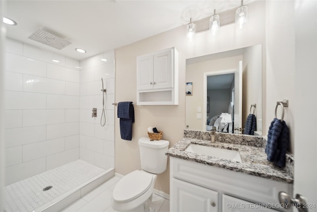 bathroom featuring a tile shower, tile patterned floors, vanity, and toilet