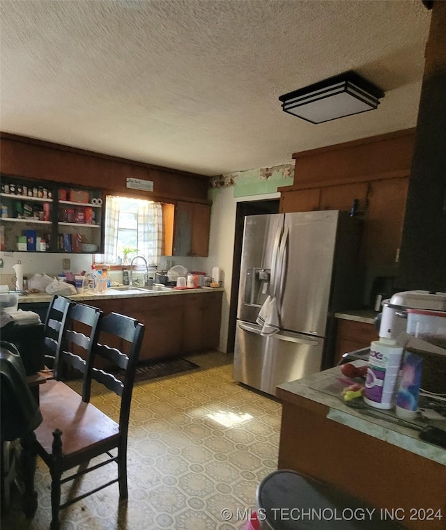 kitchen with stainless steel fridge, sink, and a textured ceiling