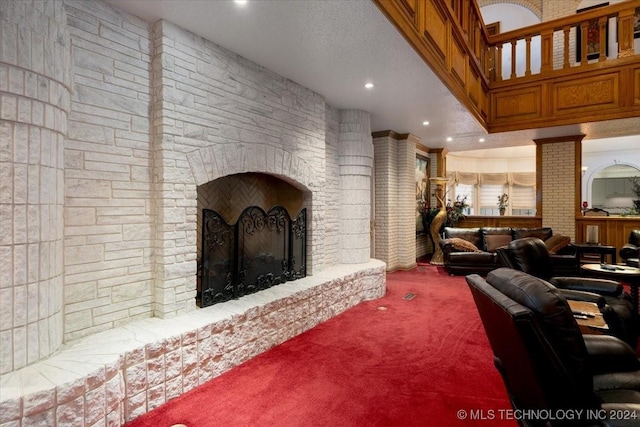 living room featuring carpet, decorative columns, and a stone fireplace