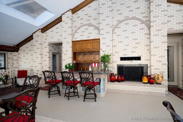 dining area with a fireplace, high vaulted ceiling, and brick wall