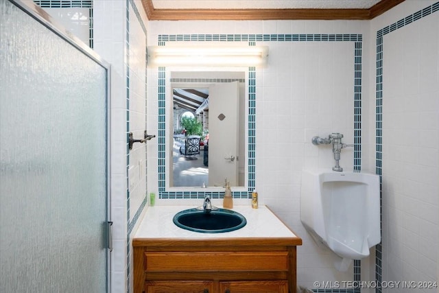 bathroom with vanity, tile walls, crown molding, and a shower with shower door