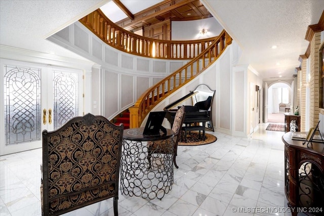 entryway with ornamental molding, a textured ceiling, and french doors