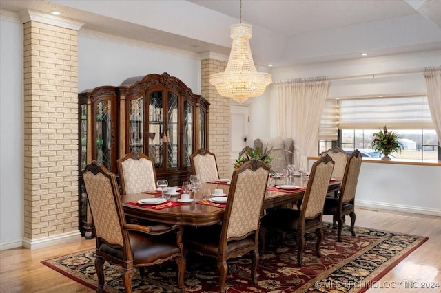 dining room featuring a raised ceiling, light wood-type flooring, and a chandelier