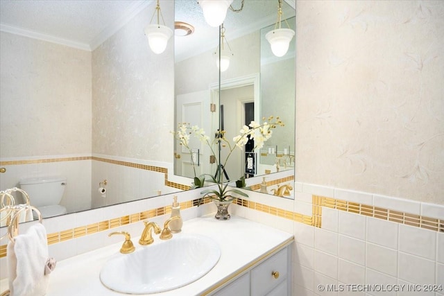 bathroom featuring vanity, toilet, crown molding, and tile walls