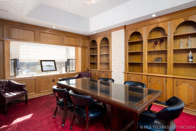 office area featuring dark colored carpet, a raised ceiling, a textured ceiling, and built in features