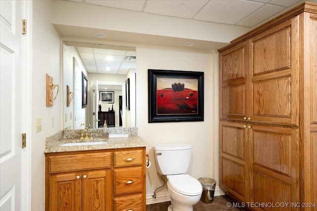 bathroom with vanity, toilet, and a paneled ceiling