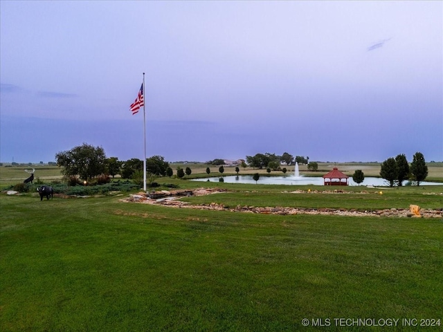 view of property's community with a water view and a lawn