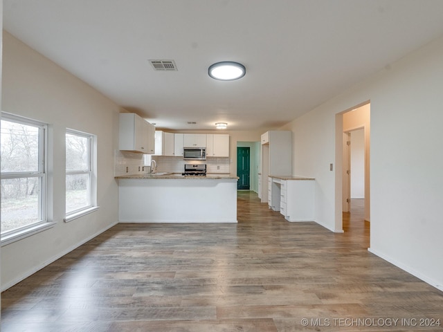 kitchen featuring kitchen peninsula, white cabinetry, stainless steel appliances, and light hardwood / wood-style floors