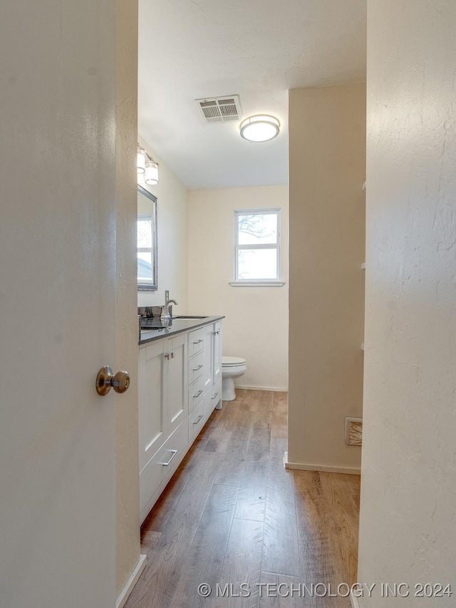 bathroom with hardwood / wood-style floors, vanity, and toilet