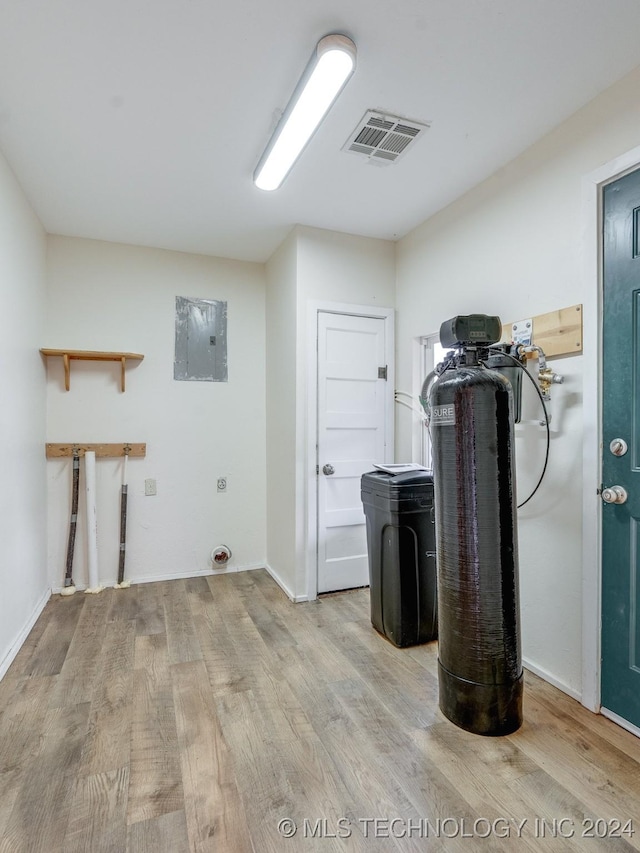 laundry area featuring electric panel and light hardwood / wood-style flooring