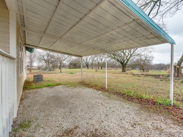 view of patio / terrace with central air condition unit, a rural view, and a carport