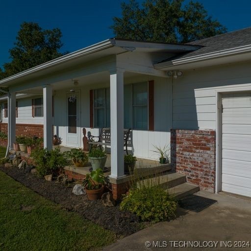 doorway to property with a porch and a garage