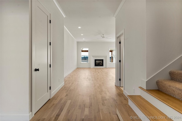 corridor with light hardwood / wood-style floors and crown molding