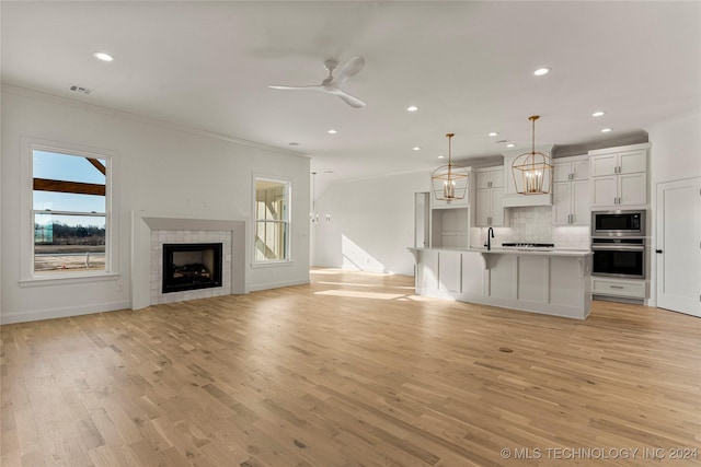 unfurnished living room with ornamental molding, a healthy amount of sunlight, and light hardwood / wood-style floors