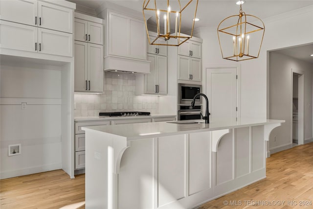 kitchen with decorative light fixtures, an inviting chandelier, stainless steel gas cooktop, and an island with sink