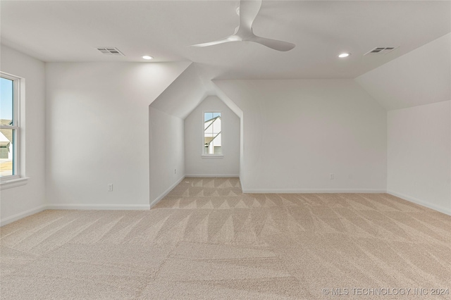 additional living space with ceiling fan, light colored carpet, and vaulted ceiling